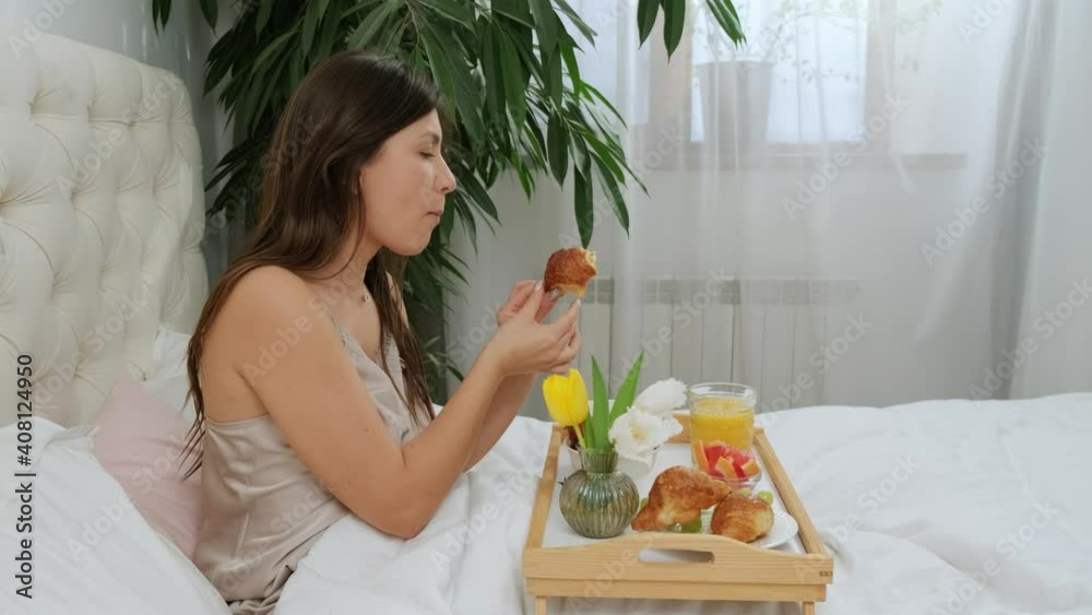 Close to a young woman eating croissant and drinking a cup of coffee, the perfect morning with breakfast in bed. Close to a young woman eating croissant and drinking a cup of coffee, the perfect morning with breakfast in bed.