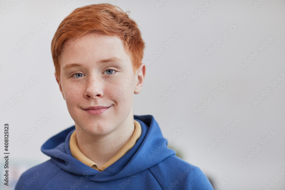 Head and shoulders portrait of freckled red haired boy looking at camera and smiling while standing against white background, copy space Head and shoulders portrait of freckled red haired boy looking at camera and smiling while standing against white background, copy space