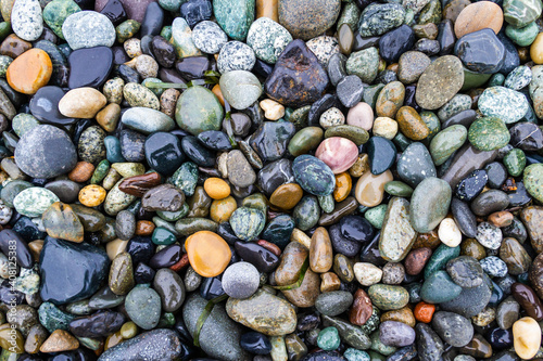 Colorful smooth rocks on the beach covered in water.