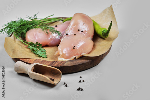 Raw chicken fillets on wooden plate with spoon