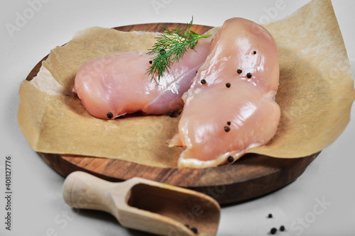 Raw chicken fillets on wooden plate with spoon