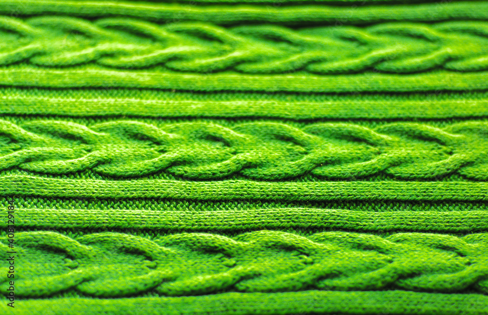 knitted background of light green color. Woolen fabric with pattern of braids. Aran patterns tied with knitting needles. knitted background of light green color. Woolen fabric with pattern of braids. Aran patterns tied with knitting needles.