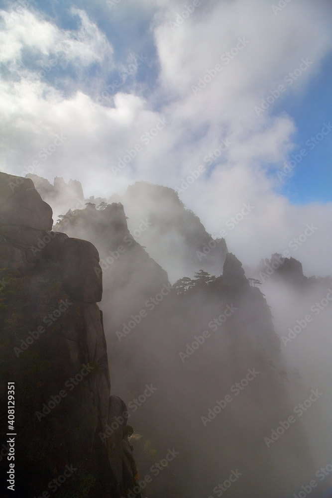 Fototapeta premium Berg im Nebel mit Sonnenschein