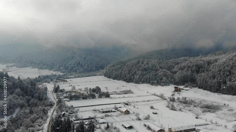 Flying over a village covered with snow in the Carpathian Mountains on a cloudy winter day Flying over a village covered with snow in the Carpathian Mountains on a cloudy winter day