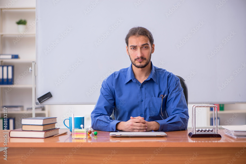 Young male teacher physicist sitting in the classroom Young male teacher physicist sitting in the classroom