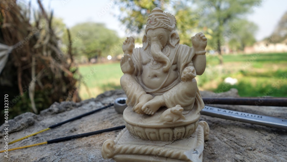 White statue of lord ganesha in sitting action with marble stone. The Lord of all wisdom and knowledge