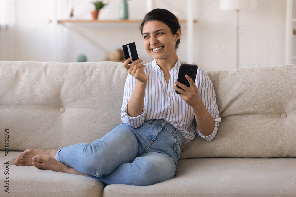 Excited indian female bank customer use phone to make easy secure payments online in convenient app. Glad mixed race lady dream of spending bonus cashback received on credit card for internet paying Excited indian female bank customer use phone to make easy secure payments online in convenient app. Glad mixed race lady dream of spending bonus cashback received on credit card for internet paying