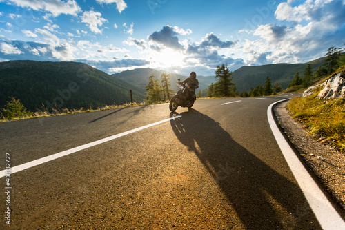 Foto Motorbiker riding in Austrian Alps in beautiful sunset dramatic sky
