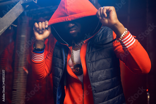 Rapper in red hoodie poses in grunge studio