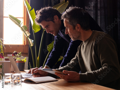 Colleagues working on laptop in a cosy environment. Creative business men. Hipsters working remotely while confined.
