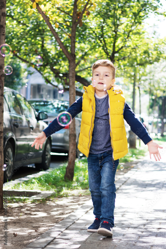 Full length of kid playing with soap bubbles on a sidewalk. Full length of kid playing with soap bubbles on a sidewalk.