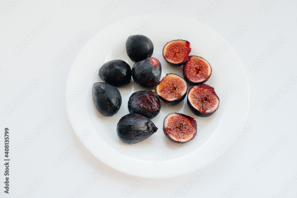 Ripe and sweet figs cut and arranged in a plate on a white background with free space. Fruits and vegetarianism Ripe and sweet figs cut and arranged in a plate on a white background with free space. Fruits and vegetarianism