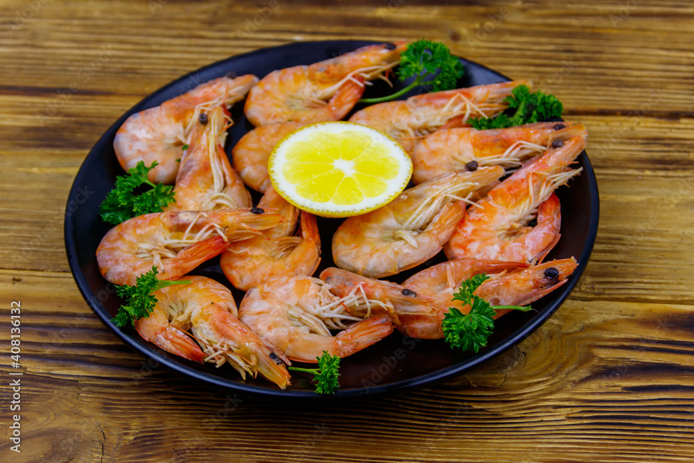 Red boiled prawns with lemon and parsley on wooden table Red boiled prawns with lemon and parsley on wooden table