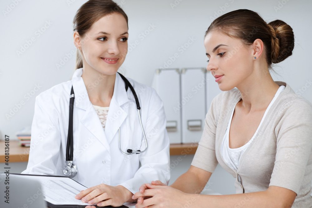 Doctor and patient are sitting and discussing health examination results in clinic office. Health care, medicine and good news concepts Doctor and patient are sitting and discussing health examination results in clinic office. Health care, medicine and good news concepts