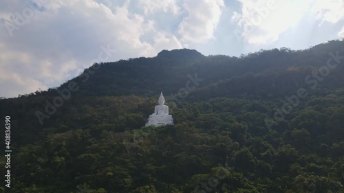 Luang Por Khao, Wat Theppitak Punnaram, a 4k footage towards this landmark of a Giant White Buddha Statue in Pak Chong, Thailand. Great afternoon sky and mountain trees changing colours. photo