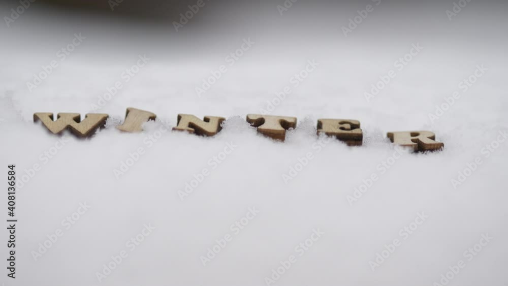 Winter concept, intro title written with wooden letters in snow, winter landscape tilt up rack focus Winter concept, intro title written with wooden letters in snow, winter landscape tilt up rack focus