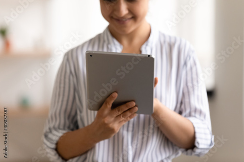 Cropped view of smiling female user holding new model of electronic tablet computer scrolling data on wide touchscreen. Happy young woman navigating internet using modern gadget digital pad. Close up