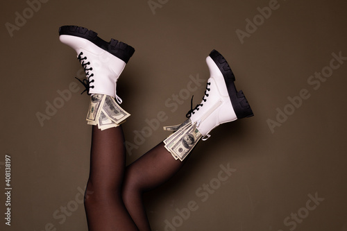 Close up view of dollar bills in shoes on dark background.Boots full of money on a dark background. Image isolated on dark green studio background.
 photo