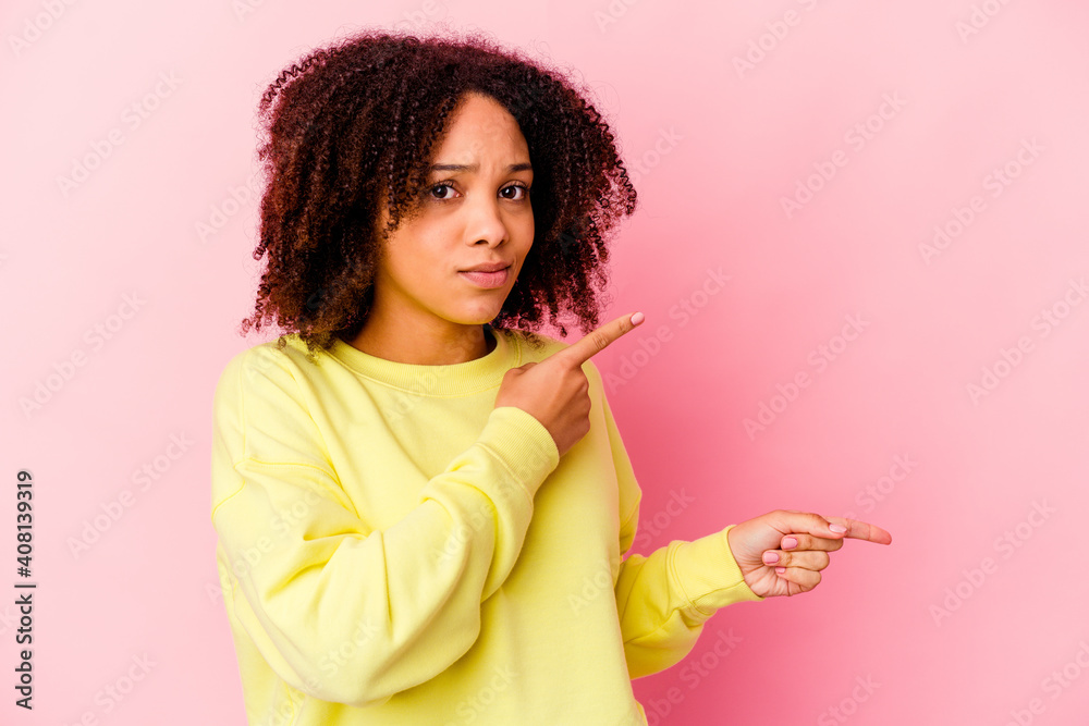 Young african american mixed race woman isolated shocked pointing with index fingers to a copy space. Young african american mixed race woman isolated shocked pointing with index fingers to a copy space.