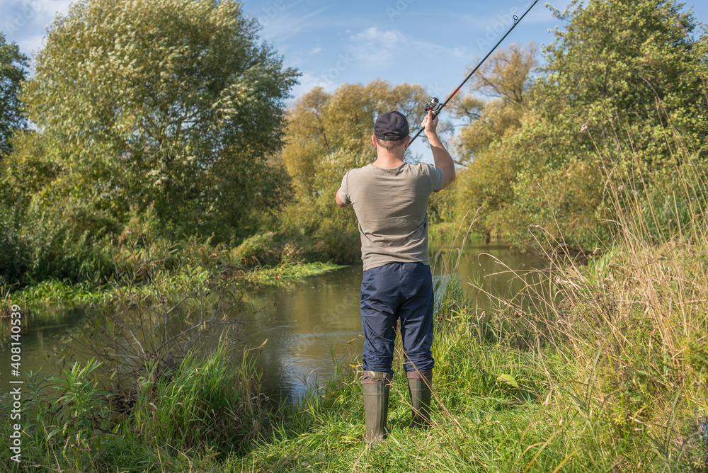 Fisherman holding a fishing rod by the river. Summer sunny day Fisherman holding a fishing rod by the river. Summer sunny day