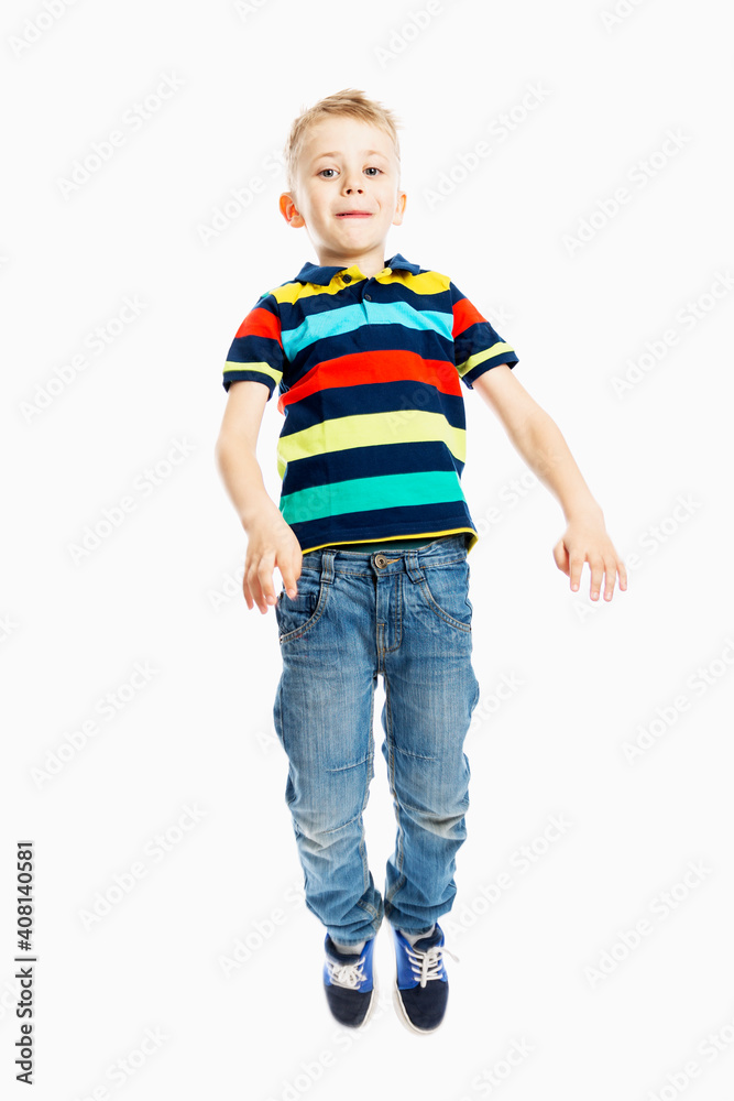 A boy in jeans and a multicolored T-shirt is jumping. White background. Vertical. A boy in jeans and a multicolored T-shirt is jumping. White background. Vertical.