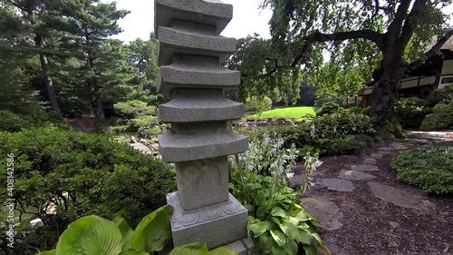 Steadicam shot moving through Japanese garden past stone pagoda and weeping cherry tree to view of exterior of house. photo