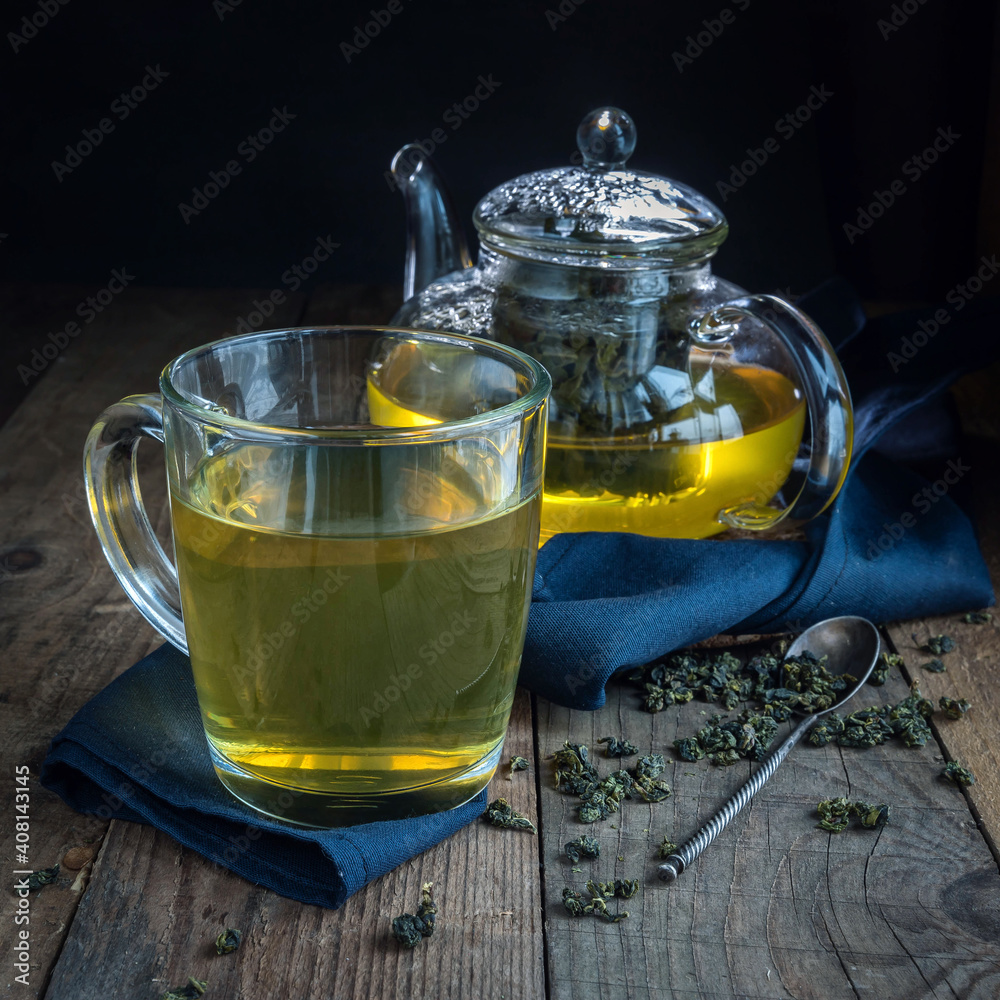 Cup of chinese green tea and teapot on a blue cloth. Chinese green tea on a wooden table and brew . Cup of chinese green tea and teapot on a blue cloth. Chinese green tea on a wooden table and brew .