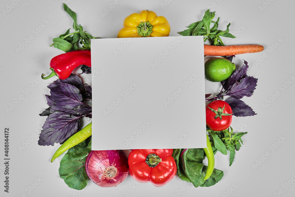 Fresh vegetables, carrots, peppers, greens, carrots, onion around white paper