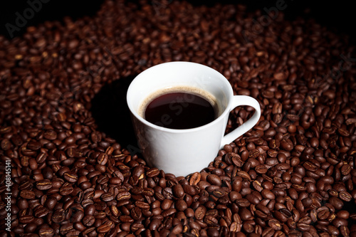 Coffee beans and white coffee cup on black background