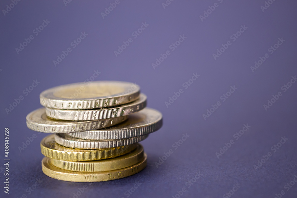 Stack of coins from different countries on a purple background Stack of coins from different countries on a purple background