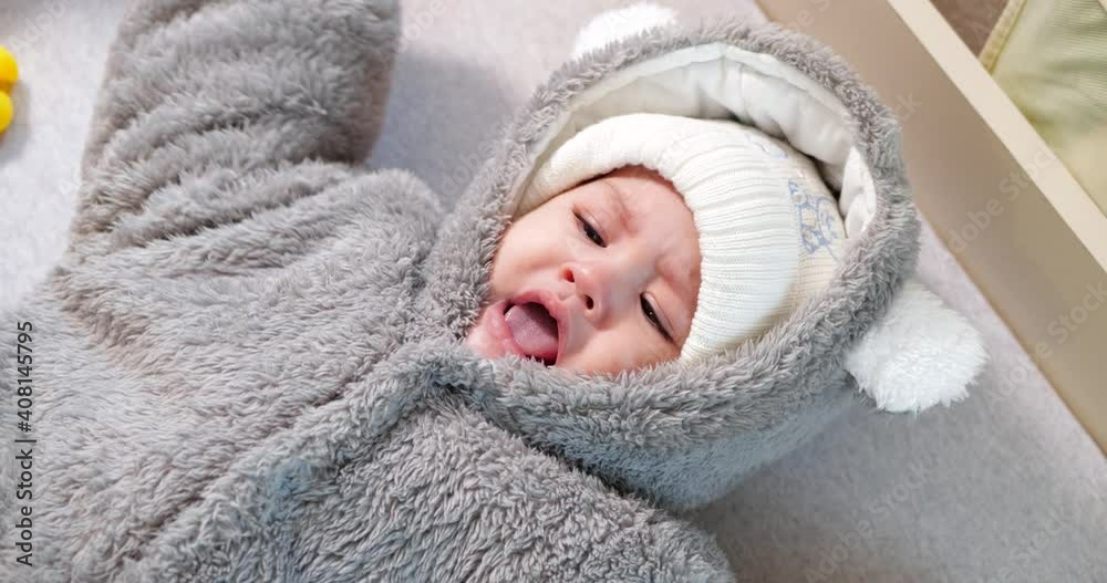 Mom dresses a crying little boy on the bed. Medicine, healthcare, family innocence, pediatrics, happiness, infant concepts Mom dresses a crying little boy on the bed. Medicine, healthcare, family innocence, pediatrics, happiness, infant concepts