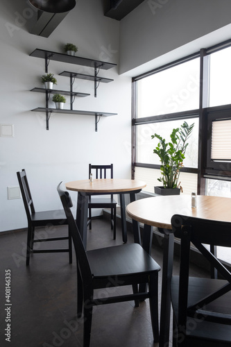 interior of a small cozy cafe or a working dining room without people. Light walls, dark furniture, lots of natural light