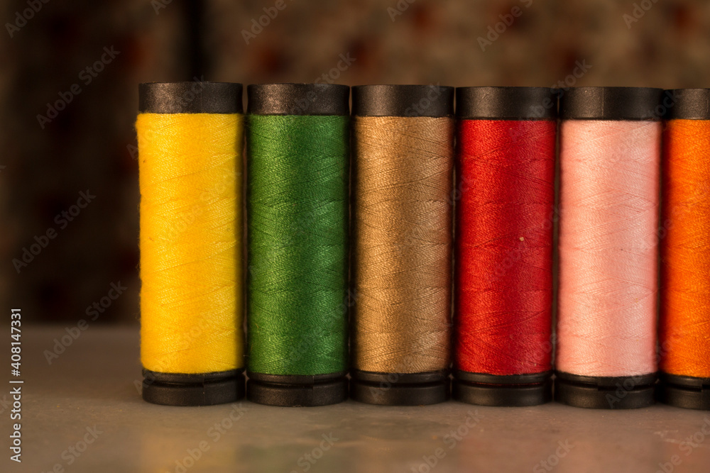 Multicolored thread spools lined as a row
Multicolored thread spools lined as a row