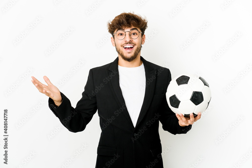 Young indian soccer coach isolated receiving a pleasant surprise, excited and raising hands.