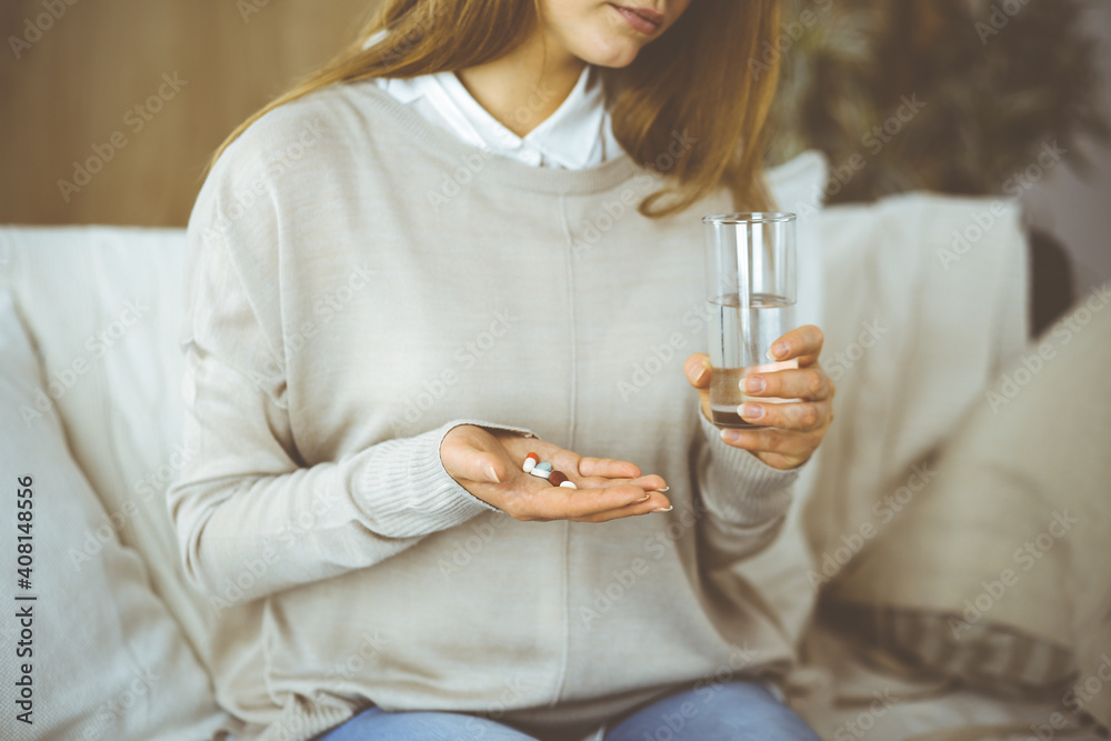 Close-up woman holding pills time to take medications, cure for headache, high blood pressure pain killer drugs at home. Stay at home concept during Coronavirus pandemic Close-up woman holding pills time to take medications, cure for headache, high blood pressure pain killer drugs at home. Stay at home concept during Coronavirus pandemic