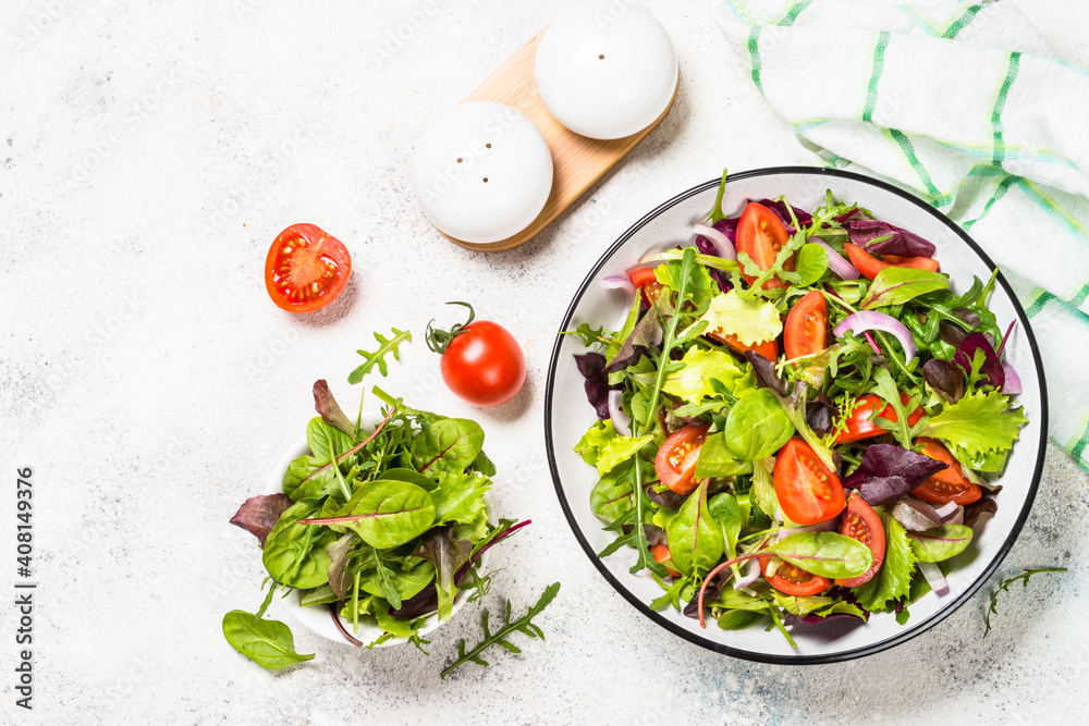 Green salad from fresh salad leaves and vegetables in white plate. Healthy vegan food. Top view image. Green salad from fresh salad leaves and vegetables in white plate. Healthy vegan food. Top view image.