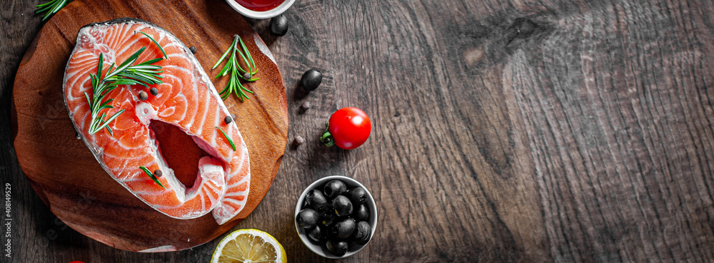 fresh raw salmon steak with tomato, lemon, olive, pepper, sauce and aromatic herbs on the wooden table background fresh raw salmon steak with tomato, lemon, olive, pepper, sauce and aromatic herbs on the wooden table background