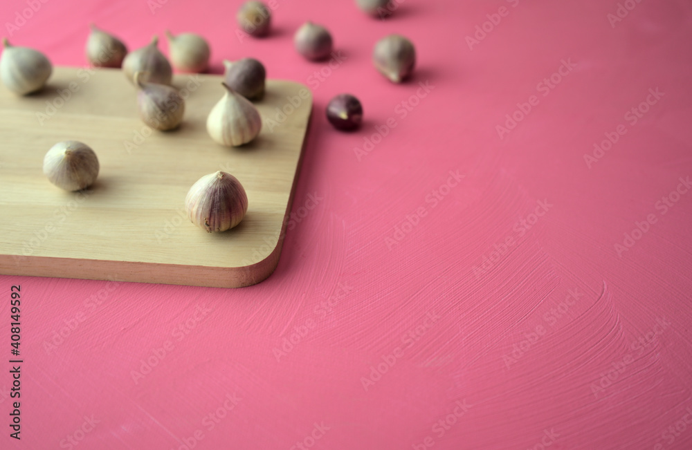 Garlic on cutting board on acrylic scratchy pink canvas background. Food, kitchen, eating photography with copy space. Garlic on cutting board on acrylic scratchy pink canvas background. Food, kitchen, eating photography with copy space.