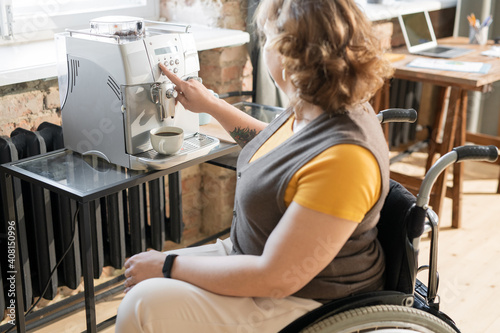 Young businesswoman in wheelchair going to make cup of coffee for herself
