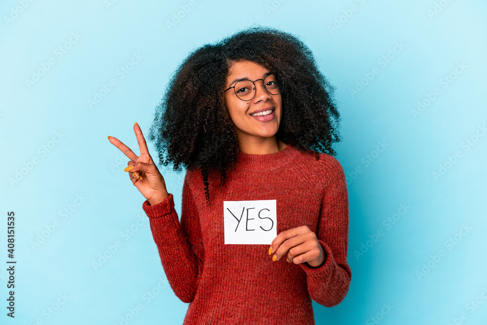 Φωτογραφία Young african american curly woman holding a yes placard joyful and carefree showing a peace symbol with fingers