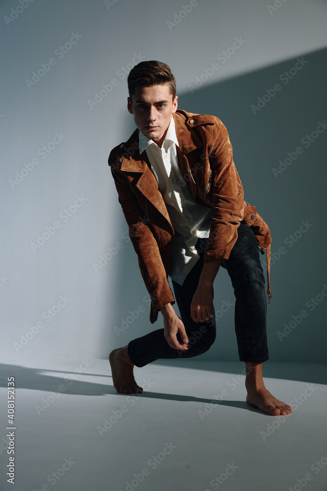 Handsome guy in a brown coat is kneeling room on the floor