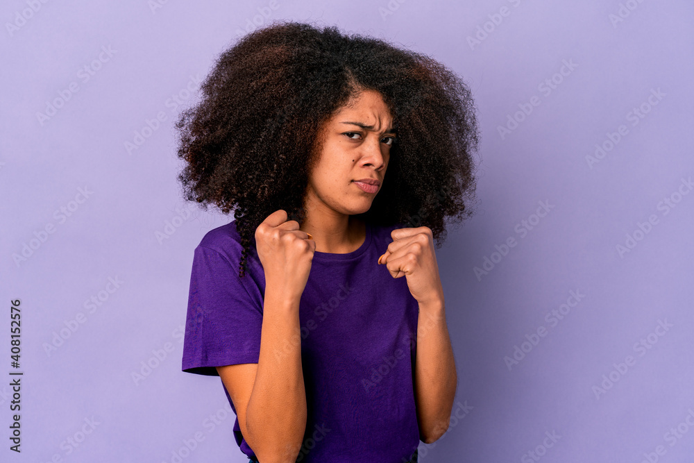 Young african american curly woman isolated on purple background showing fist to camera, aggressive facial expression. Young african american curly woman isolated on purple background showing fist to camera, aggressive facial expression.