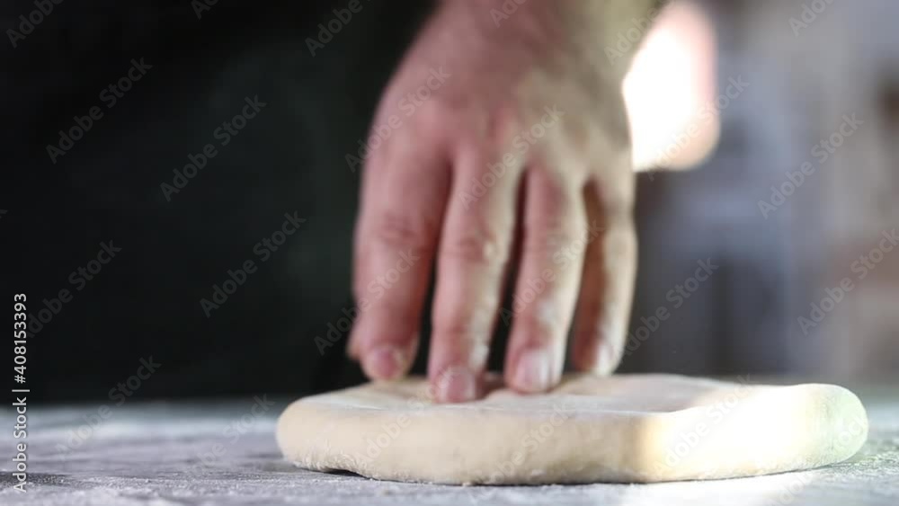 Man takes and rolls out the dough with a rolling pin Man takes and rolls out the dough with a rolling pin