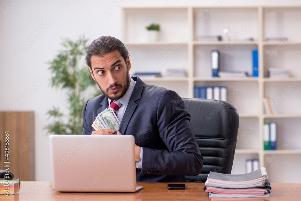 Young male employee holding banknotes in the office Young male employee holding banknotes in the office
