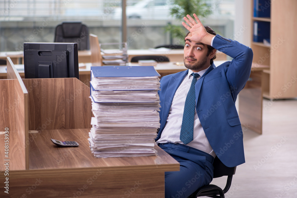 Young male employee unhappy with excessive work in the office Young male employee unhappy with excessive work in the office