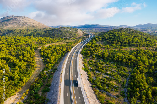 Aerial view on road. Highway throu mountain valley. View from a drone. Natural landscape in summer time from air. Travel and vacation. Transportation image