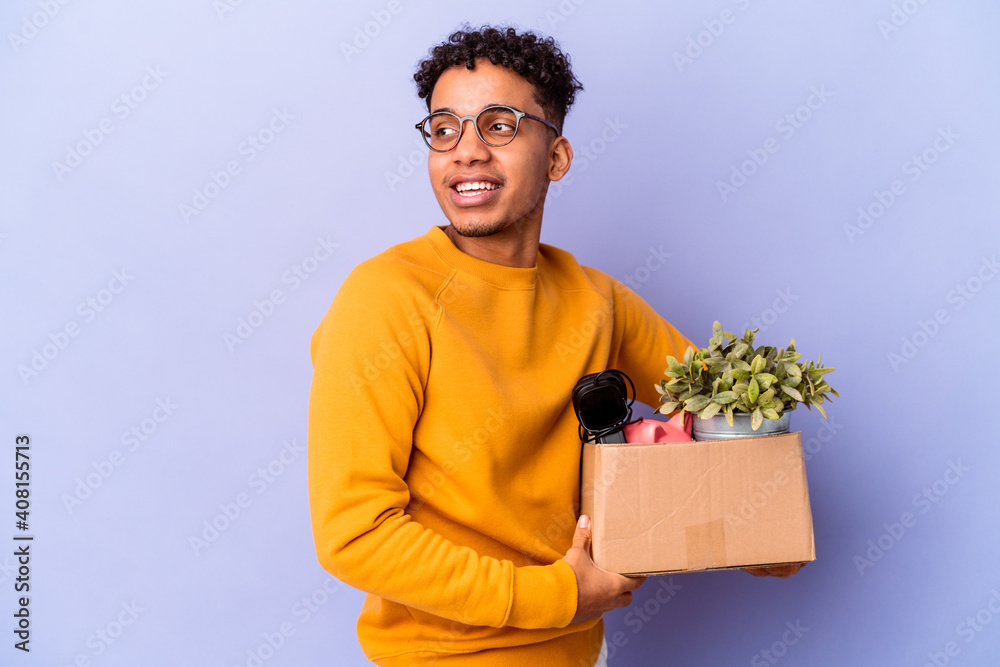 Young african american curly man isolated moving to a new home looks aside smiling, cheerful and pleasant. Young african american curly man isolated moving to a new home looks aside smiling, cheerful and pleasant.
