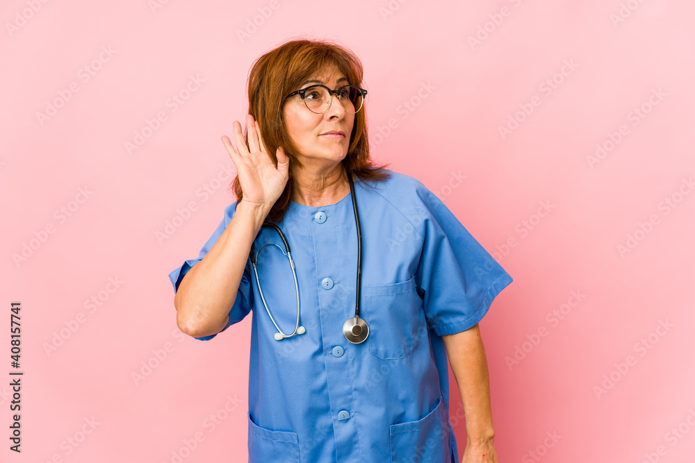 Middle age caucasian nurse woman isolated trying to listening a gossip. Middle age caucasian nurse woman isolated trying to listening a gossip.
