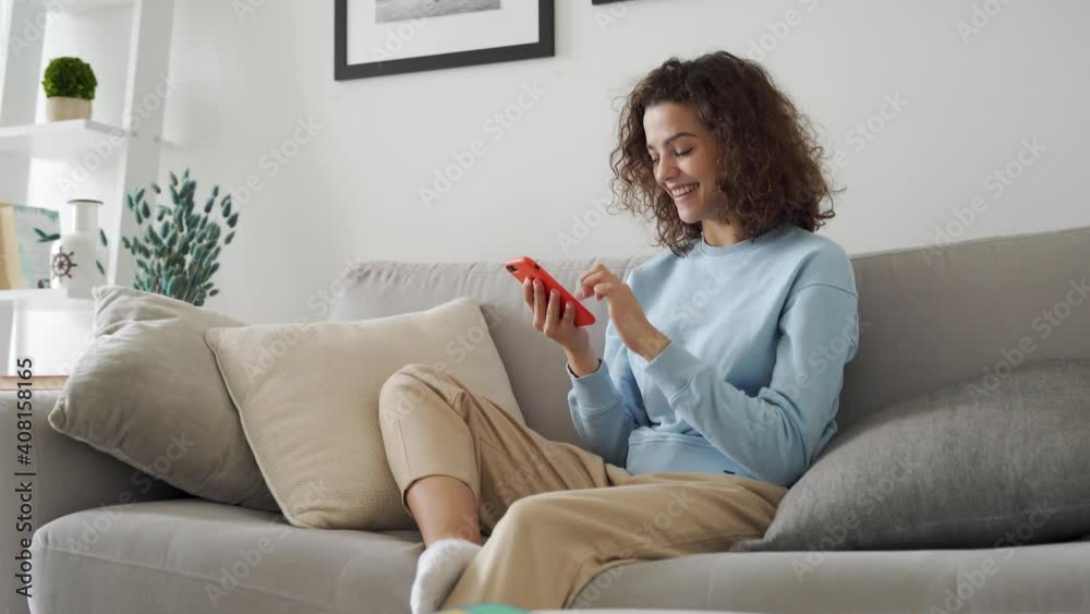 Happy hispanic teen girl holding cell phone using smartphone device at home. Smiling young latin woman blogger subscribing new social media, buying in internet, ordering products online in apps.