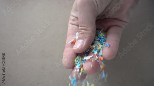Side view of micro plastics falling from a human hand. Slow-motion of waste non-recyclable plastic.  Selective focus on the hand. Environmental issues, global warming, and climate change concept.